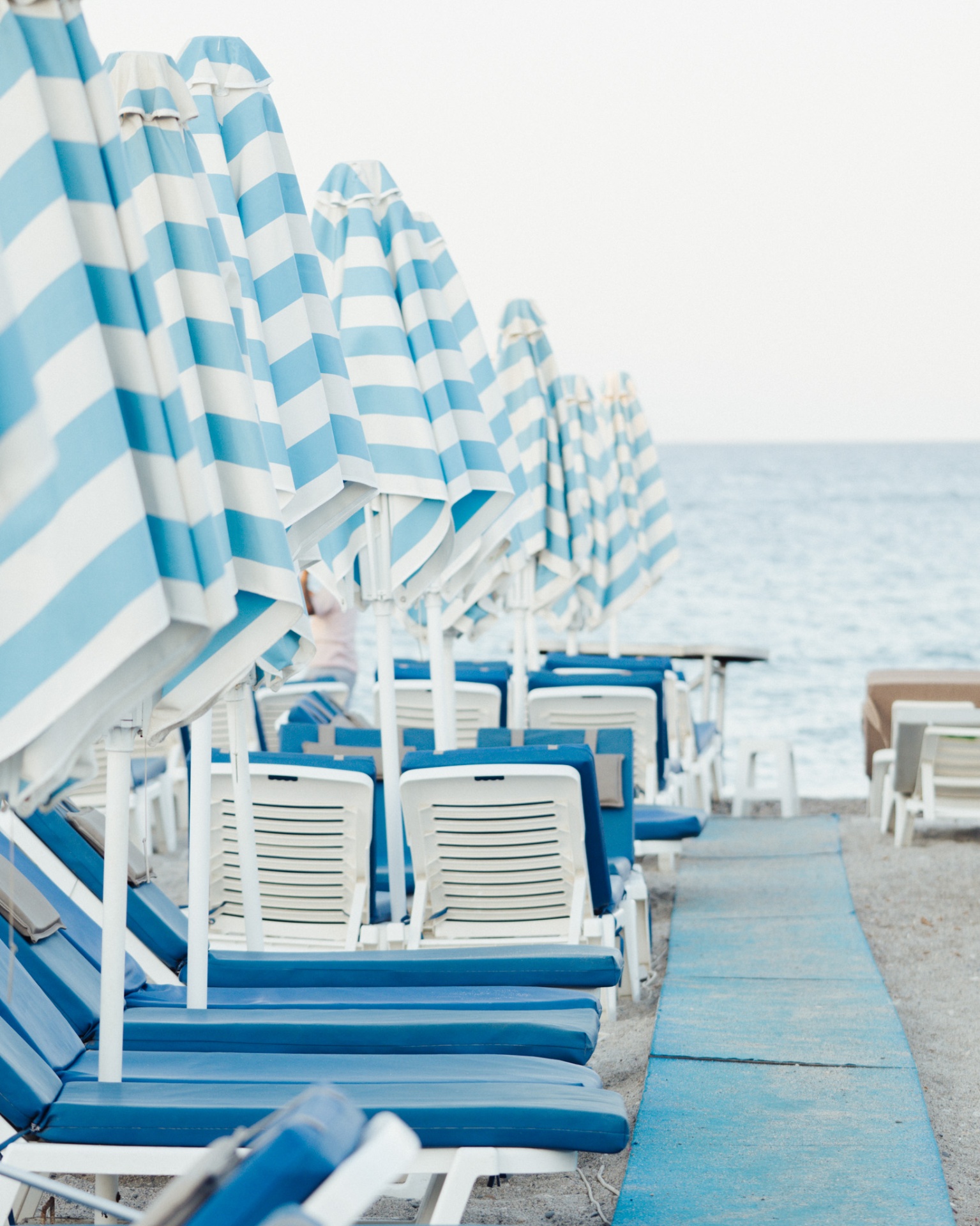 Blue striped beach umbrellas along the Aegean shore